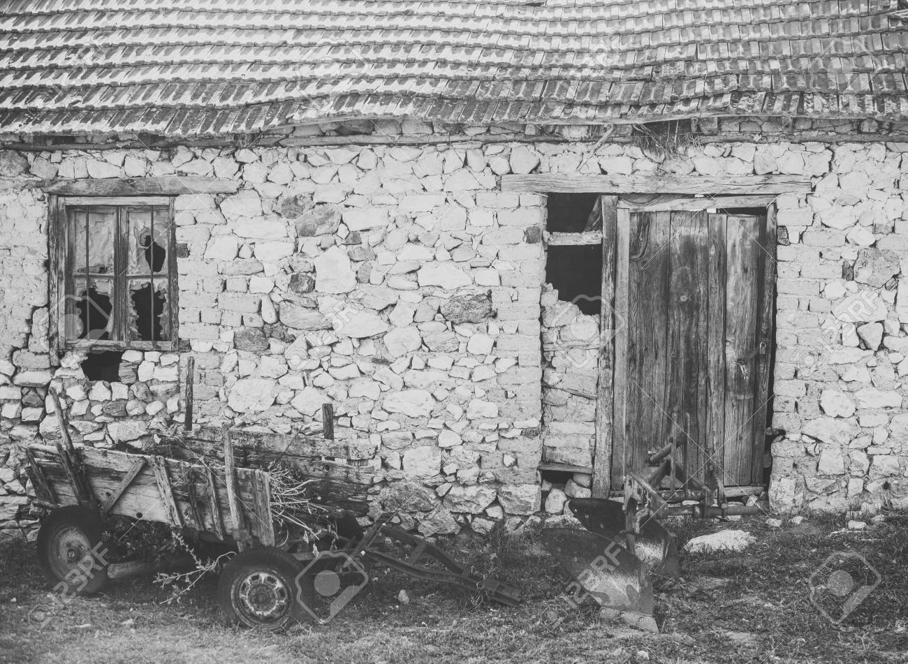 old abandoned barn. Abandoned cart next to ruins. Old cart near stone wall. District with old buildings, old building made of stones collapsing. The uninhabited house almost destroyed